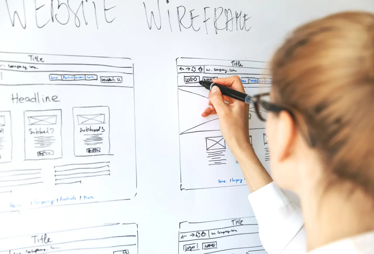 Person sketching a website wireframe on a whiteboard